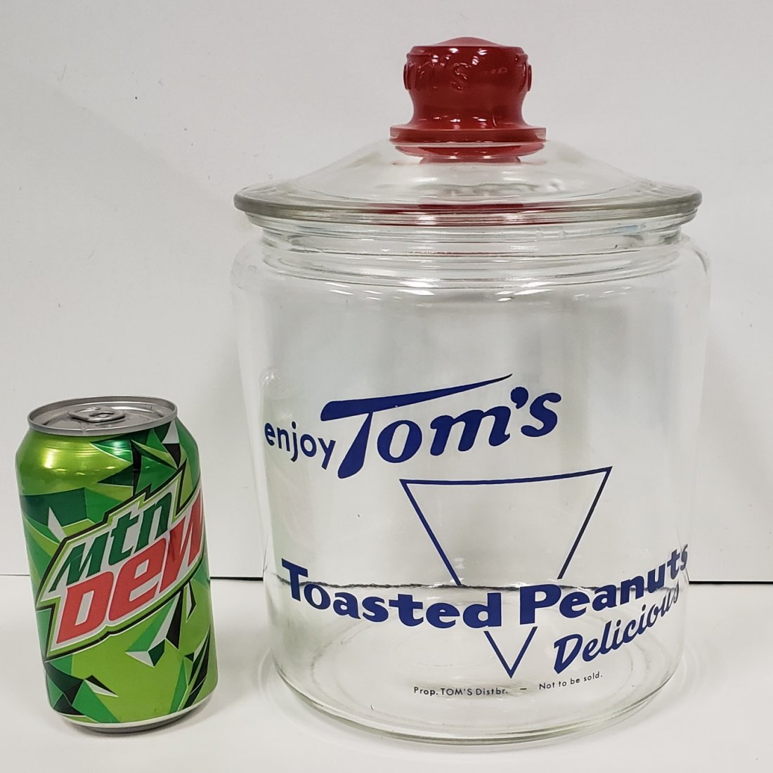 Enjoy Tom's Toasted Peanuts Delicious Jar: 11" glass jar with embossed handle on lid. Excellent condition. PLEASE READ & UNDERSTAND THE PAYMENT & SHIPPING TERMS FOR THIS AUCTION PRIOR TO PLACING BIDS. ALL BIDDERS ARE BOUND TO THE TERMS OF THE