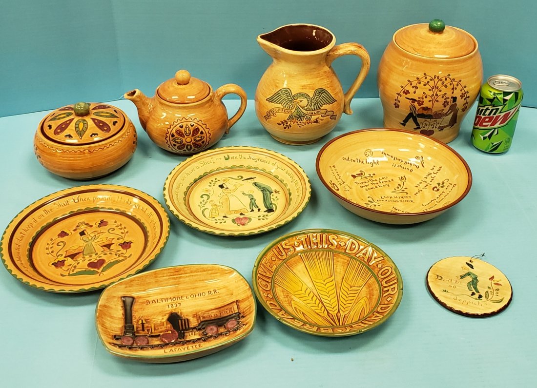 Lot of 10 Pennsburg Pottery: Lot of 10 pieces of Pennsburg Pottery including; Amish couple tree cookie jar with lid, Amish hex teapot with lid and candy jar with lid, "Don't be so doppich" wall hanger, 9" sayings bowl, patriotic 
