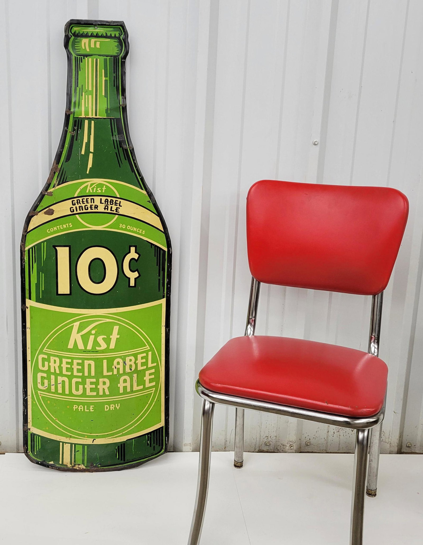 10 cent Kist Green Label Ginger Ale Die Cut Bottle Sign: Metal embossed die cut bottle sign with paint flakes, shallow bend, specks, minor stains. Marked Charles Bluman Woodstock Ontario. 16" x 47.75".PLEASE NOTE, THERE IS ONLY ONE WAY TO PAY FOR ONLINE ITE