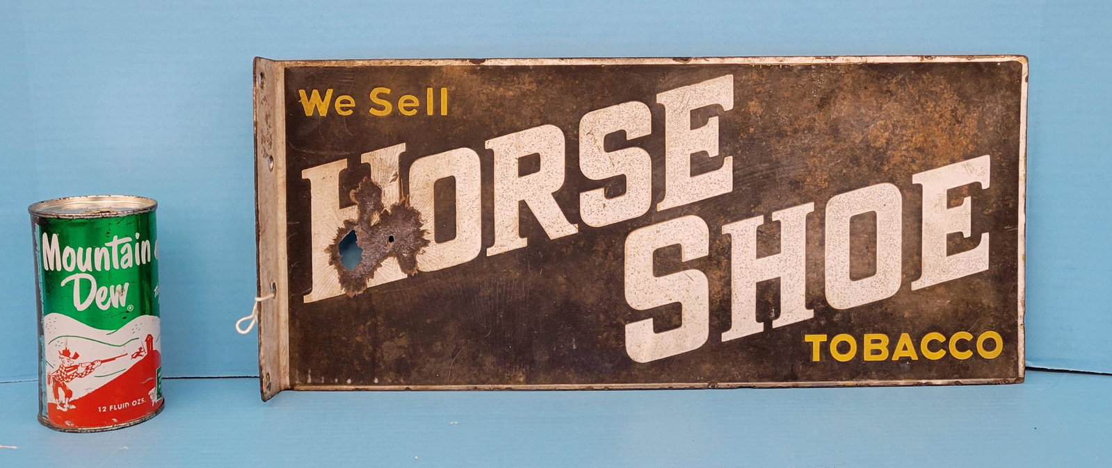 We Sell Horse Shoe Tobacco Porcelain Flange Sign: Porcelain flange with 2 holes having porcelain loss, heavy stains, scuffs and scratches in the field. 18" x 8". PLEASE NOTE, THERE IS ONLY ONE WAY TO PAY FOR ONLINE ITEMS IN THIS AUCTION WHICH IS THRO