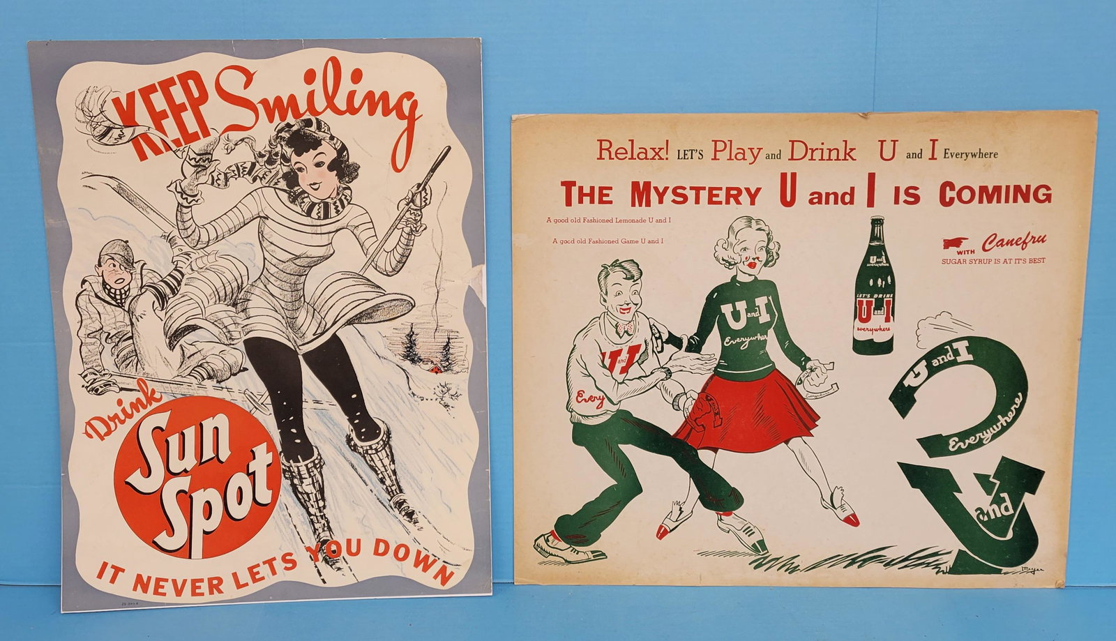 Drink Sun Spot & U and I Cardboard Advertising Signs: 16.75" x 22" 1955 Paper Sun Spot poster mounted on cardboard with good color, a few scuffs, and some small tears on right outer edge. There is also a 1" inch piece missing on the outer right edge. 22"