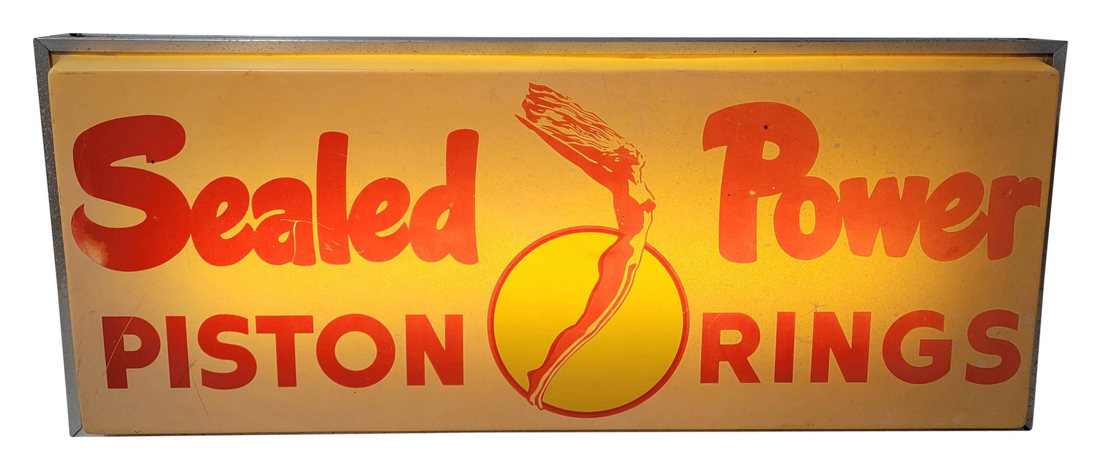 Sealed Power Piston Rings Light Up Advertising Sign: 14" x 34.5" working illuminated sign features the art deco maiden logo on a plastic face with metal housing. The plastic advertising face displays signs of age and discoloration throughout. The metal