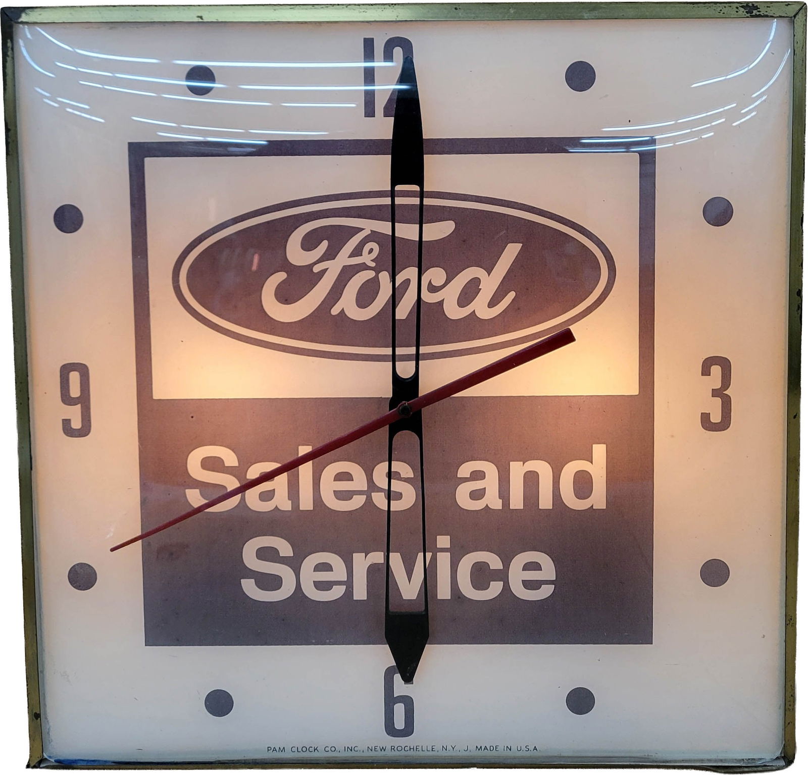 Ford Sales and Service Light Up Pam Clock: 15.5" x 15.5" working illuminated clock features the classic Ford logo with a glass face, metal trim, and metal housing. The clock hands move but the hour hand is loose. The trim and housing have typi