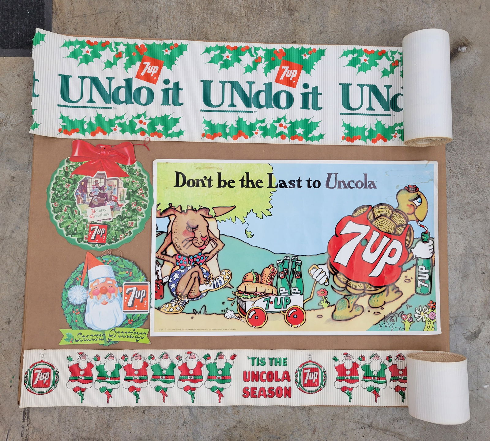 Vintage Christmas Holiday Santa 7up advertising lot with Uncola poster: Lot of 7up advertising items including a corrugated paper roll of 7up advertising with Santa graphics, 7up logo, and the slogan "Tis the Uncola Season". The roll is 6.5" h x 21 ft long when rolled out