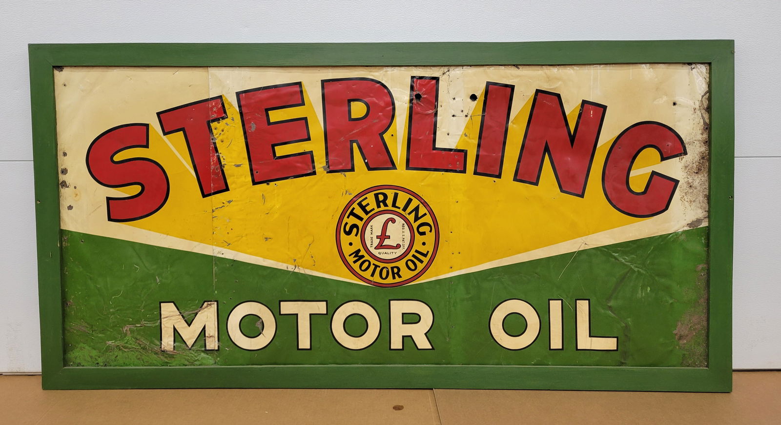 Sterling Motor Oil Single Sided Tin Sign In Wood Frame: 73" x 37" SST sign is mounted in a painted wood frame. The sign exhibits heavy wear with bends, scratches, and holes. The sign has a vertical cut through the letter 'T' and it has been nailed to a pie