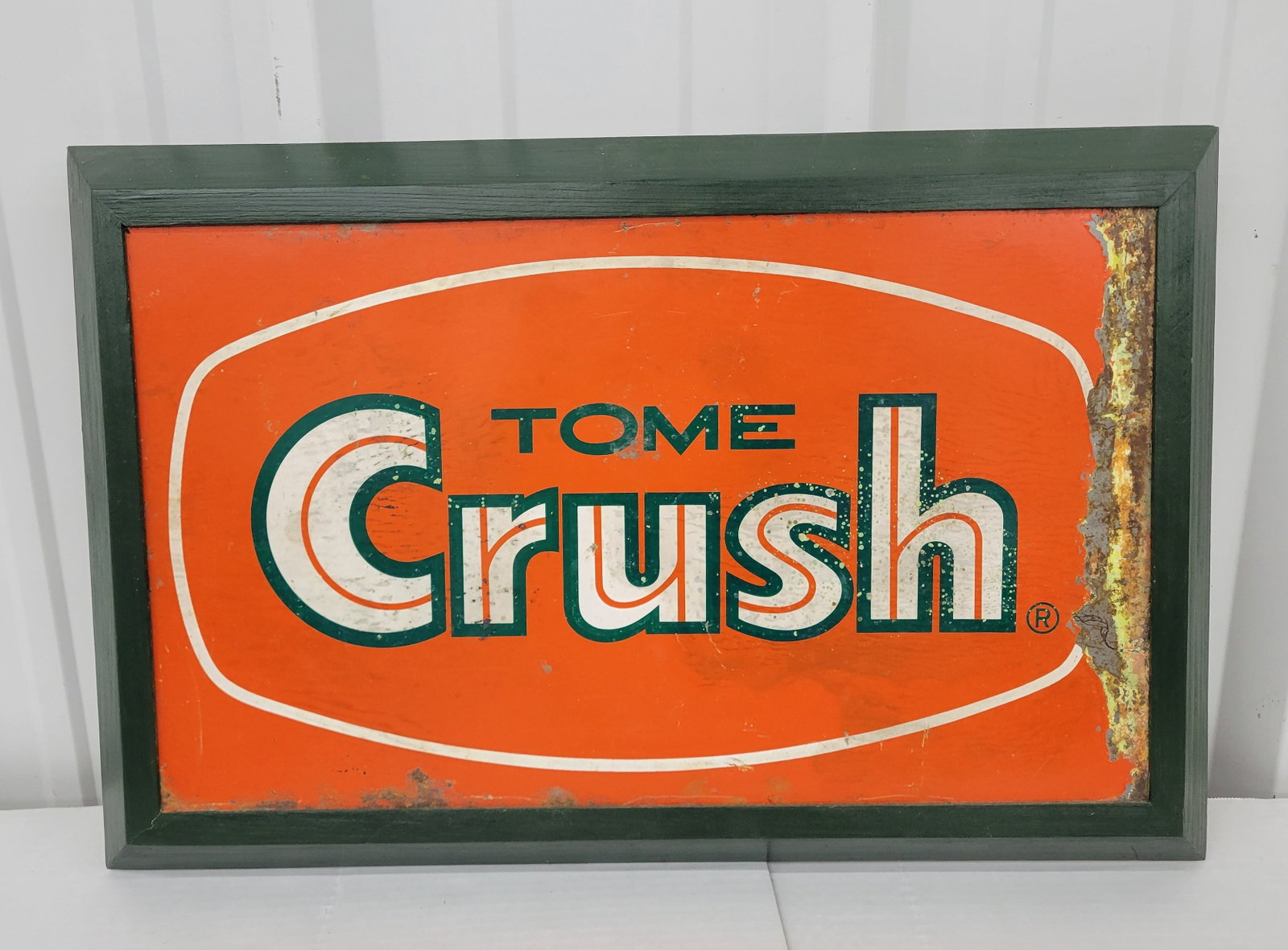 Crush Double Sided Porcelain Flange Sign In Frame: 25.5" x 16.5" DSP sign has bright colors with stains, paint flakes, and stains along the right edge. The flange section has been bent and the sign is encased in a painted wood frame. The frame is newe