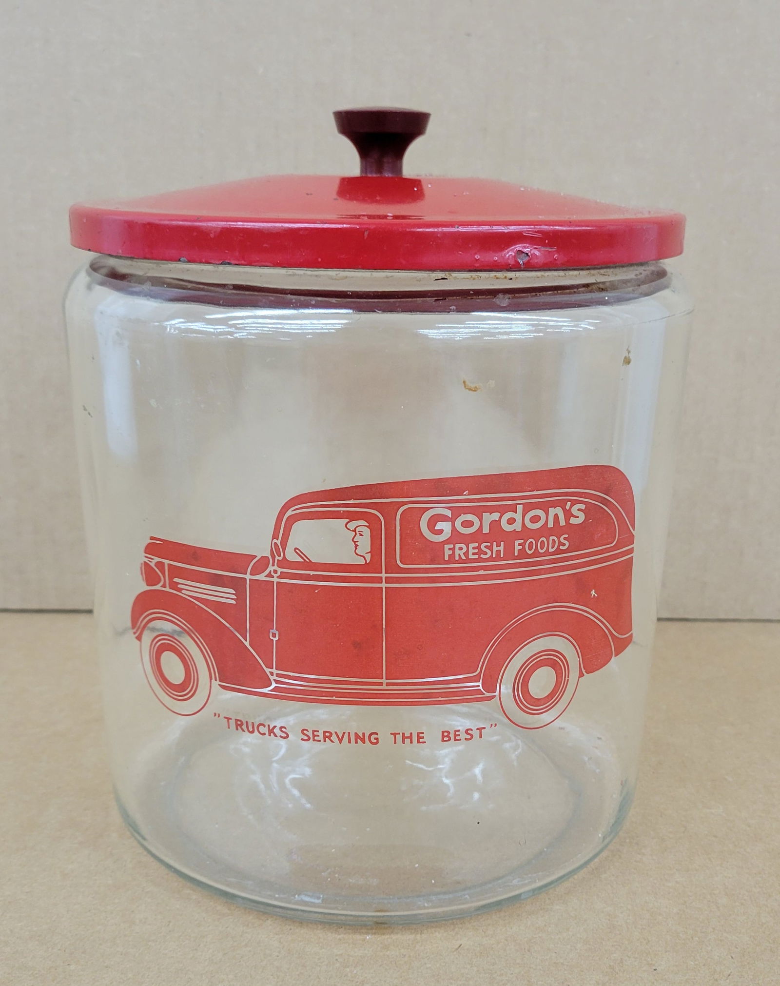 Gordon's Fresh Foods Country Store Glass Jar: 8" x 9" glass jar showcases the Gordon's Fresh Foods delivery truck and comes with a metal lid stamped with the Gordon's name on the underside. The bottom of the jar exhibits typical wear, including s