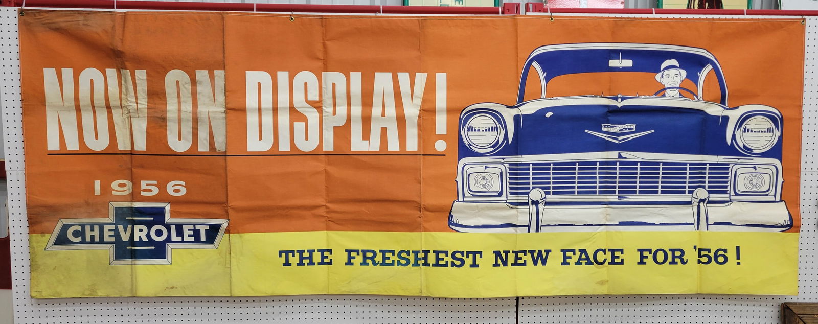 Large 1956 Chevrolet Advertising Banner: 118" x 43" large cloth Chevrolet advertising banner highlights the 1956 Chevrolet automobile. The banner exhibits good color with stains and dirt marks on the left side. There are folds throughout and