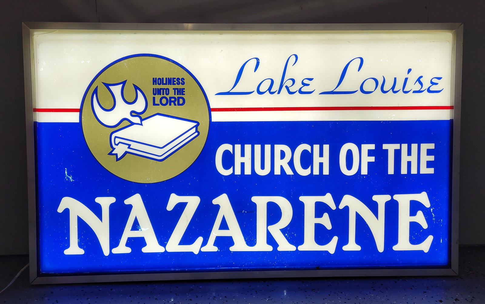 Nazareth Church Light Up Sign: 60" x 5" x 36" single sided light up sign is constructed with a plastic face and an aluminum can. The plastic face exhibits typical signs of use, including scuffs, scratches, and small areas of missin