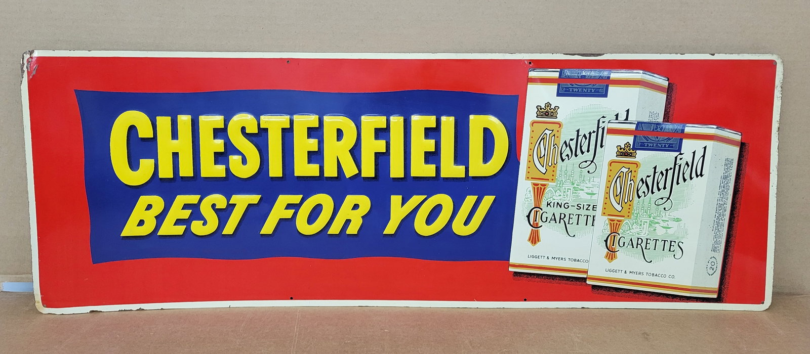 Chesterfield Best For You Embossed Single Sided Tin Sign: 34" x 12" embossed SST sign features detailed cigarette pack graphics with bright colors and good shine. The perimeter has areas of wear with paint chips and a small bend on the top edge at the corner