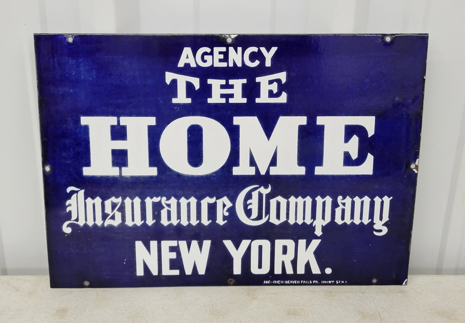 The Home Insurance Company Agency Single Sided Porcelain Sign: 20" x 14" SSP sign exhibits good gloss with very subtle fading in areas of the blue porcelain. There is minimal edge wear with a few minor flea bite chips. Ing-Rich Beaver Falls.