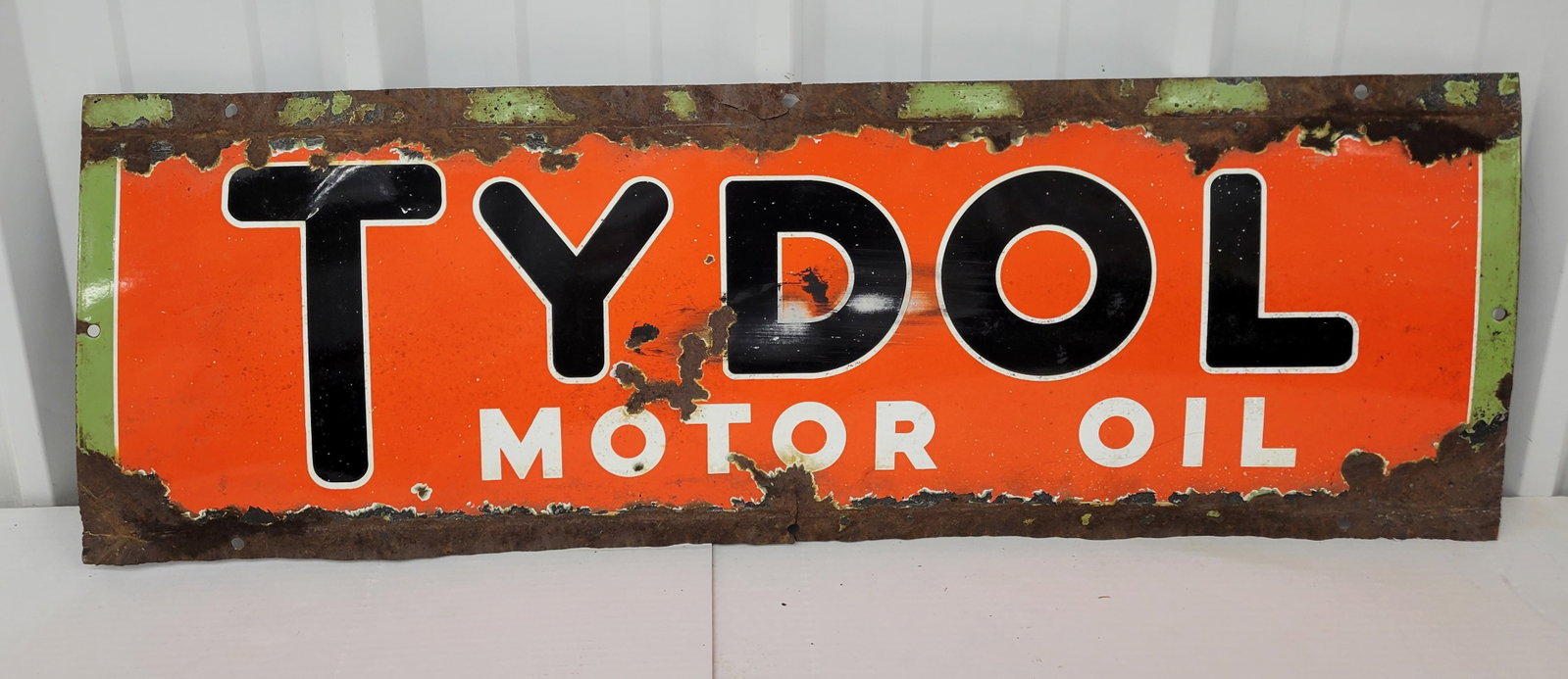 Tydol Motor Oil Single Sided Porcelain Sign: 42" x 14" SSP sign shows significant signs of wear, including chips across the surface and edge deterioration with considerable porcelain loss.