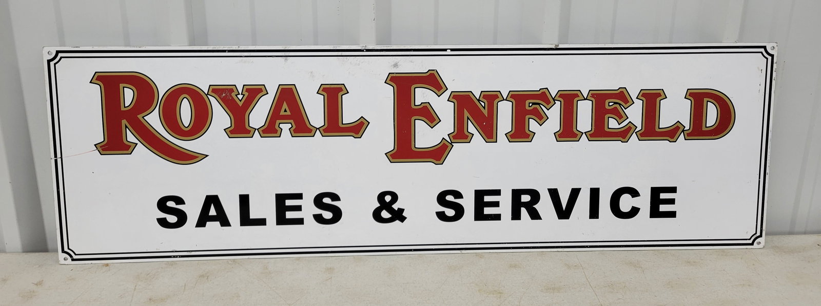 Royal Enfield Sales and Service Single Sided Sign: 47.25" x 14.25" single sided sign made of thick aluminum with an applied decal. There are several scratches in the field and around the perimeter.