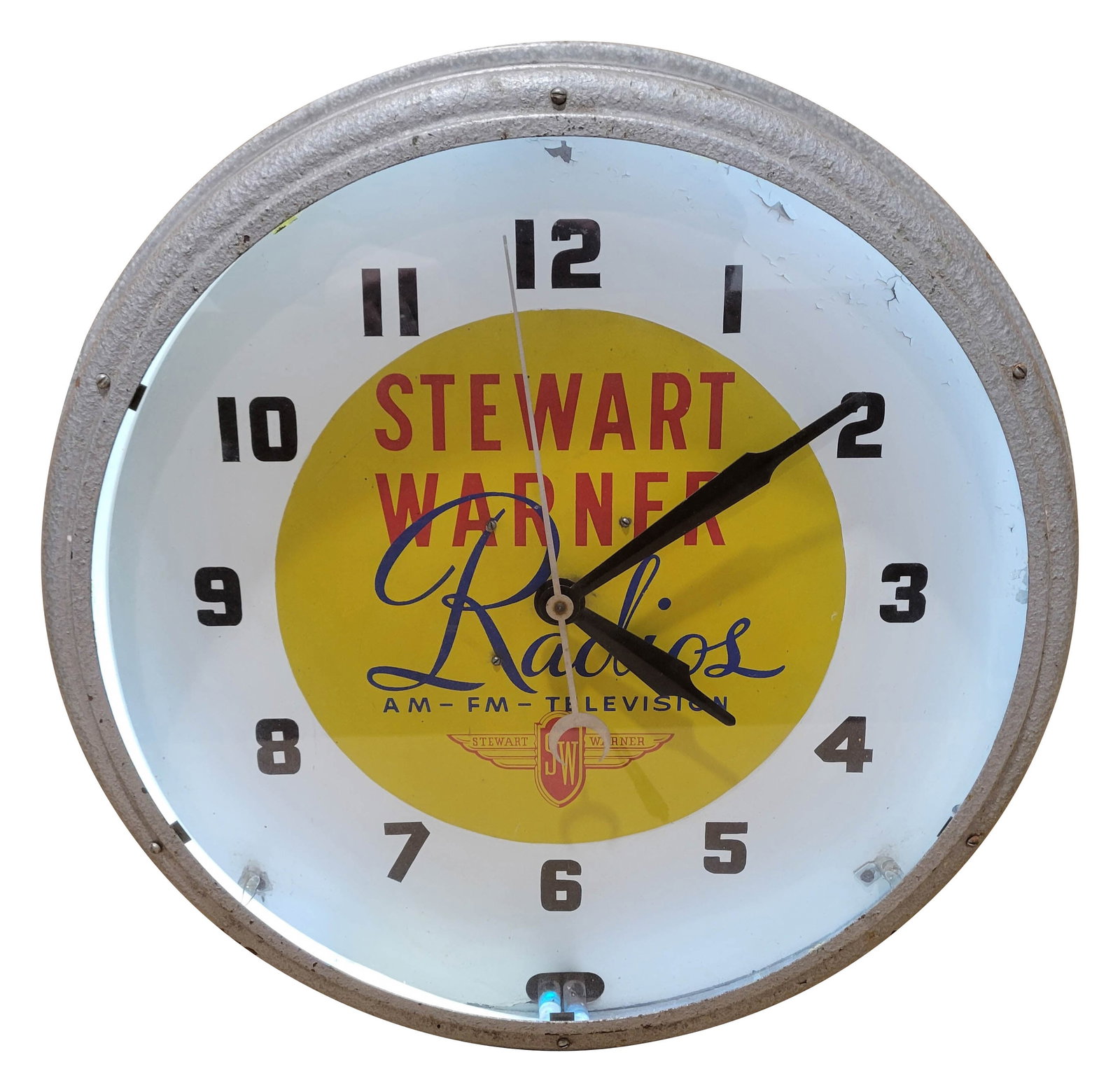 Stewart Warner Radios Television Neon Clock: 21" x 7" octagonal working counter top clock features white neon. The clock has a glass face and metal housing. It displays bright colors with normal signs of wear on the metal housing.
