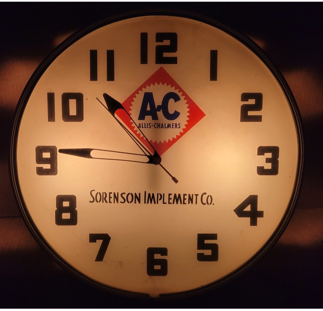 Allis Chalmers Sorenson Implement Co. Light Up Clock: 18.5" x 4"d illuminated clock is in very good working condition featuring a glass face, interior advertising face with logo, and a metal can. It displays well and functions as it should with minor wea