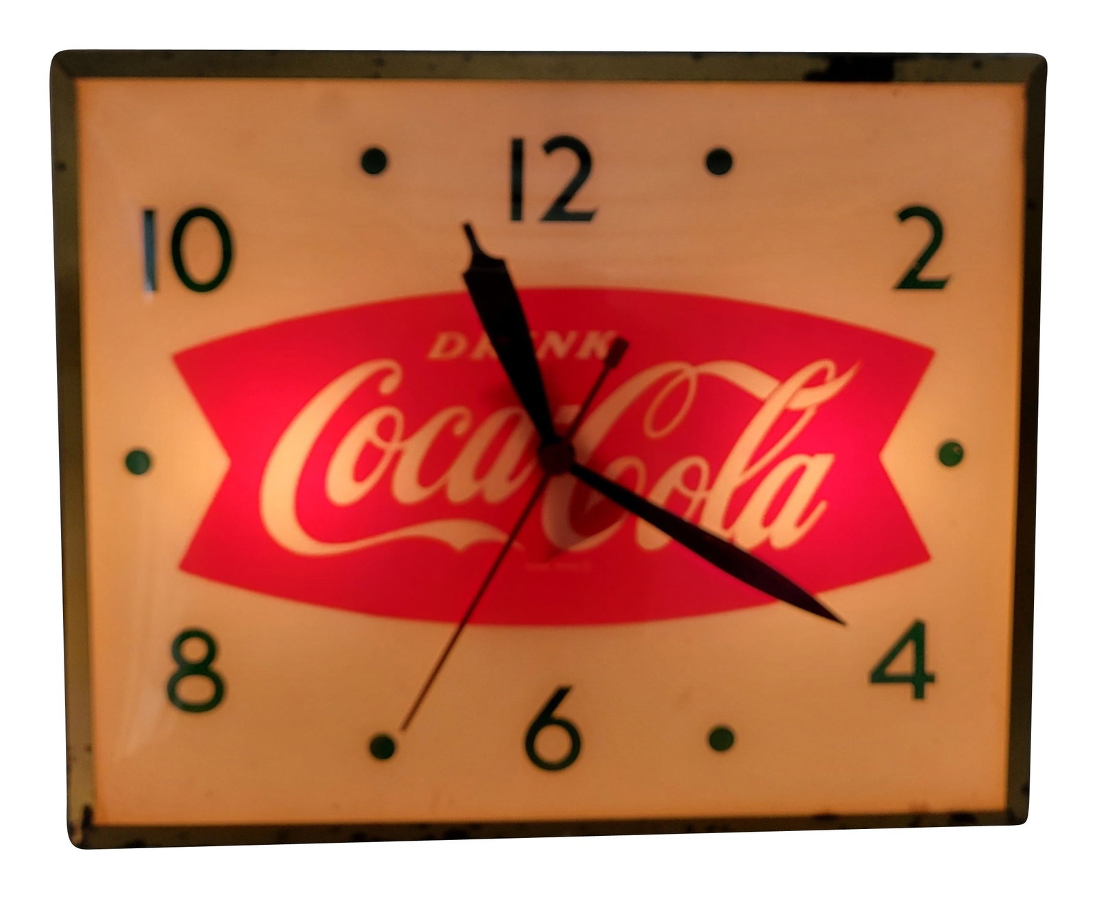 Drink Coca Cola Light Up Advertising Clock With Fishtail Logo: 16"x 13" working illuminated clock features a glass face, gold toned metal trim, and a metal can. The inner face exhibits bright color and the clock hands turn when pugged in. The gold toned trim has 