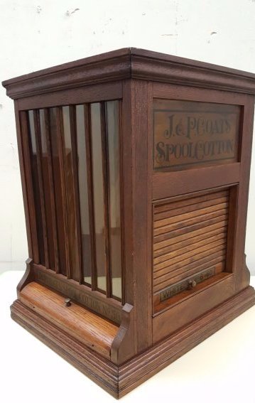 J&P Coats Spool Cabinet: Original 4 sided spool cabinet with glass columns to display spool on opposite sides of the cabinet and sliding roll up doors on the other two sides which hold additional spools. There are 4 doors on 