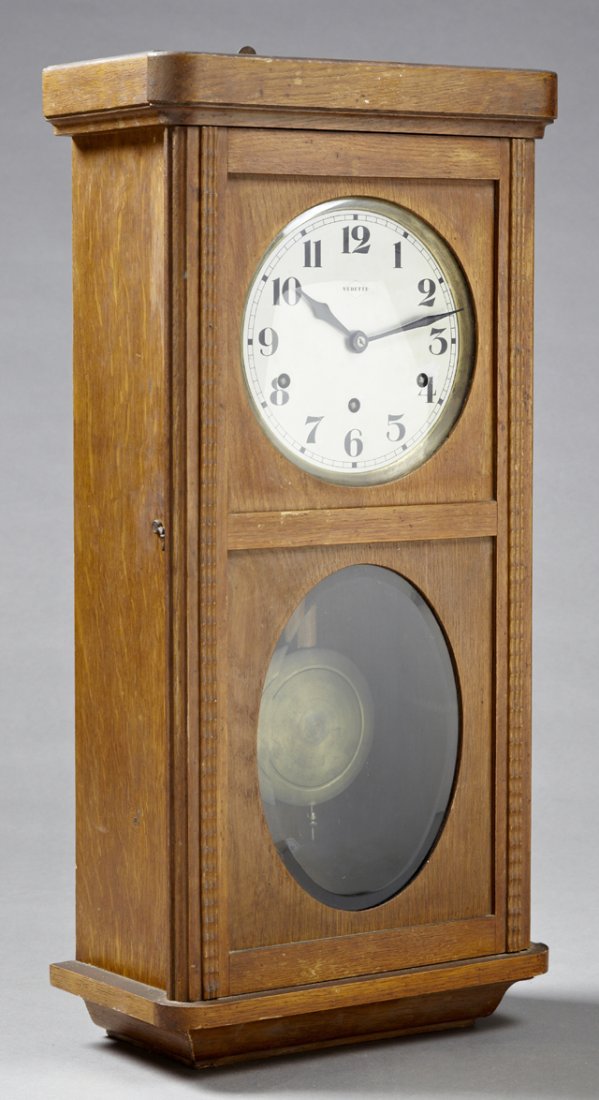 French Carved Oak Wall Clock, early 20th c., by: French Carved Oak Wall Clock, early 20th c., by Vedette, time, strike, and chime, the steel face over an oval beveled glass pendulum window, with brass pendulum, H.- 29 1/2 in., W.- 13 1/4 in., D.- 6