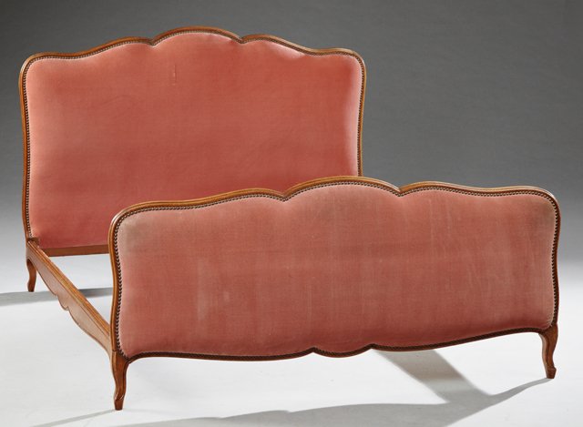 French Louis XV Style Carved Beech Bed, 20th c., the: French Louis XV Style Carved Beech Bed, 20th c., the serpentine arched headboard with an upholstered panel on cabriole legs, joined to a like constructed footboard, in pink velvet upholstery with nail