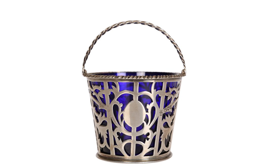 A Victorian silver sugar basket: A Victorian silver sugar basket, Charles Stuart Harris, London 1891, of pierced pail form with ropetwist swing-handle and blue glass liner. 7.5cm