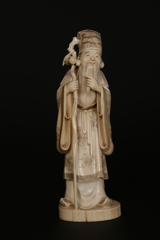A Japanese ivory Okimono: A Japanese ivory Okimono, Meiji period, modelled as Jurojin standing holding a staff, two character mark to base. 19cm