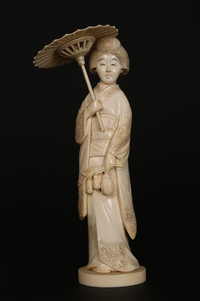 A Japanese ivory Okimono: A Japanese ivory Okimono, Meiji period, modelled as a Geisha holding a parasol, signed red plaque inset to base. 17.5cm