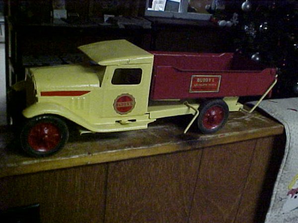 Vintage Buddy L Dump truck: Vintage steel Buddy L dump truck. Measuring 19"l x 6-1/2"t x 6"w. Repaint & labels. Original wheels complete w/tailgate. No lights or battery box.