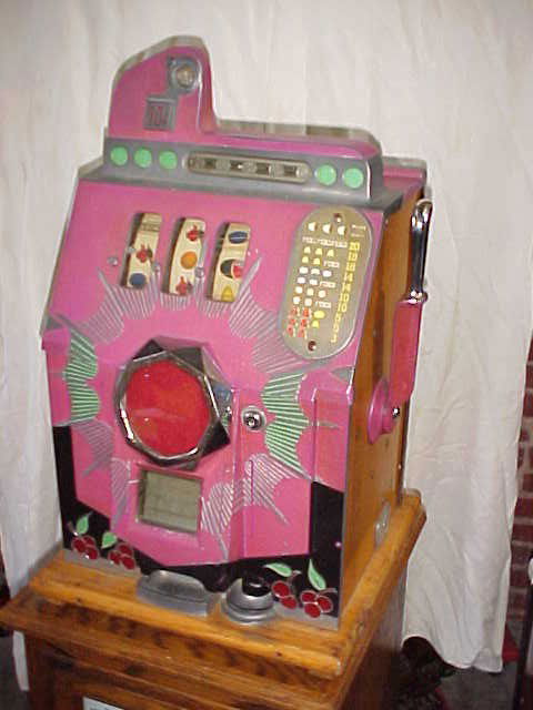 Mills Melon front 10 cent slot machine circa 1930: Mills Melon front 10 cent slot machine circa 1930's. Original paint, working condition. Pink case w/cherrys. 1 arm bandit. Oak base. Measures 26"tall x 16"wide x 15"deep.