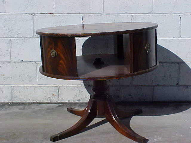 Tooled leather top mahogany revolving drum table.: Tooled leather top mahogany revolving drum table. Original finish. Duncan Phyfe styling legs. Missing one brass handle. Revolving bookshelf drum style table. Measures 27" x 32"