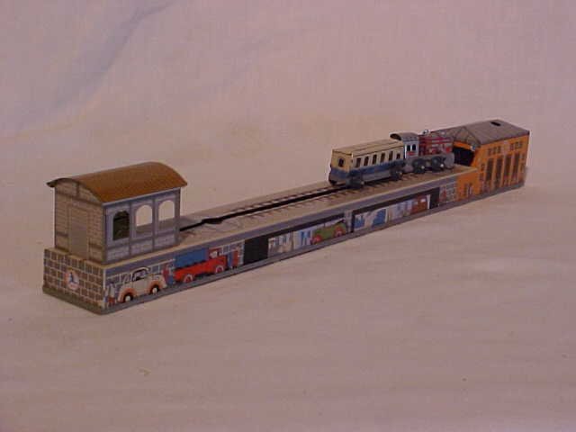 Tin litho wind-up train station toy: Tin litho wind-up train station toy. Made by Schylling. With original box. Measures 2 1/2"H x 1 3/4"W x 15"L
