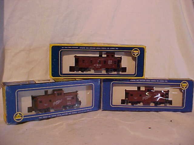 Lot of 3 AHM model train cars: Lot of 3 AHM (Associated Hobby Manufacturers) model train cars. Consists of (2) Frisco 1274 and AT &SF cabooses. Still in original boxes. HO scale. Measures 2"H x 1 1/2"W x 5"L
