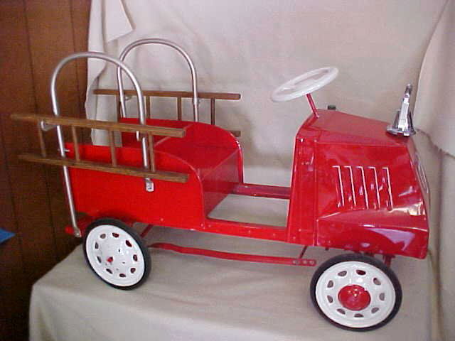 Red fire engine peddle car: Red fire engine peddle car w/2 wooden ladders. Measures 38 1/2"L x 19". Has been professionaly restored.