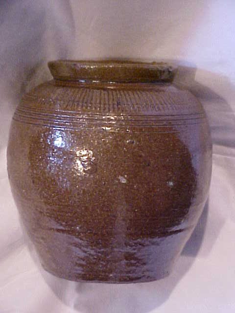 Early brown decorated jar w/ovid shape.: Early brown decorated jar w/ovid shape. Lots of decorations around shoulder. Good condition. Measures 6"tall x 6"wide.