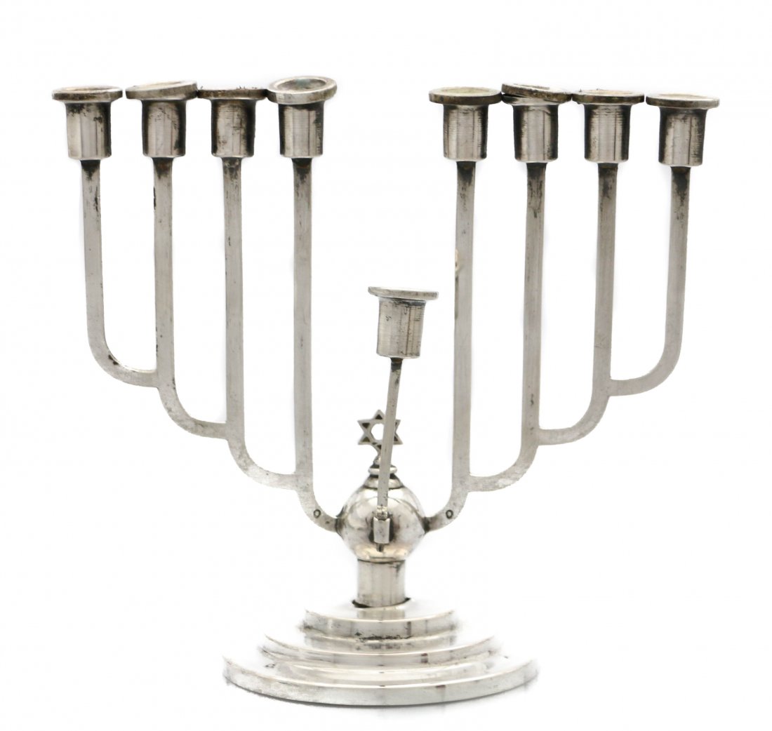 A SILVER ART DECO CHANUKAH MENORAH: Austria, Circa 1920 Round base with the Star of David in the center, with Austrian silver marks and maker's mark. Height 7.5 inches