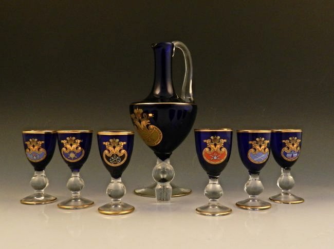 A Set of English Cobalt & Gold Cups: A 7 piece set 19th century, English Cobalt with a gold trim to the top and bottom, each depicting a royal crown logo Measures: 3 1/2 inches (each cup), larger handled cobalt piece measuring: 8 1/2 inc