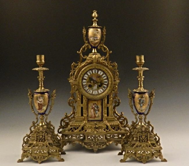 Sevres Clock Set: A fabulous 3 piece Sevres clock set depicting two figures, 19th/20th c Measures: 21 inches (clock), 14 inches each candle holder Marked on dial made in France