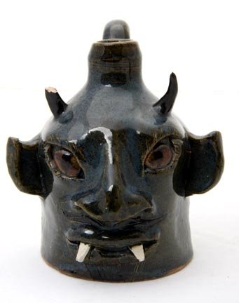 Lin Craven "Fanged Devil face jug". Fired and glaz: Lin Craven "Fanged Devil face jug". Fired and glazed pottery, signed and dated 1999, and measures 4 1/2 x 4 (chipped horn)