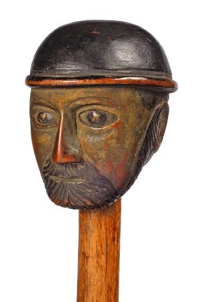 Folk Art Cane- C. 1920- A detailed carved folk-art : Folk Art Cane- C. 1920- A detailed carved folk-art head, oak shaft and a metal ferrule. H. 2" x 2 ½" O.L. 34 ½" $350-$450