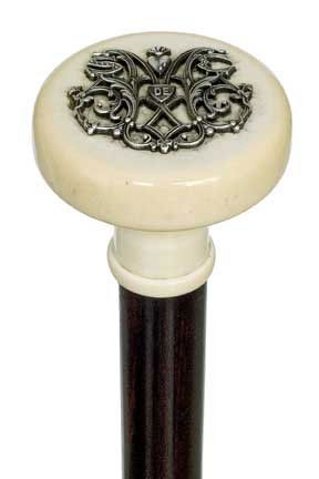 Ivory Dress Cane-Late 19th Century-Carved ivory kno: Ivory Dress Cane-Late 19th Century-Carved ivory knob with applied silver badge, ebony shaft and a long ivory ferrule-H. 1 ½" x 2", O.L. 35 ¼"-$400-$600