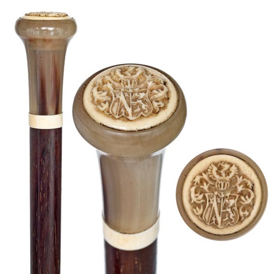 Aristocrats Cane- Circa 1880-Horn and elephant ivor: Aristocrats Cane- Circa 1880-Horn and elephant ivory carved with coat of arms, ivory collar, rosewood shaft and a horn ferrule-H. 2 ½" x 1 ¼", OL. 37 ½" $600-$1.000