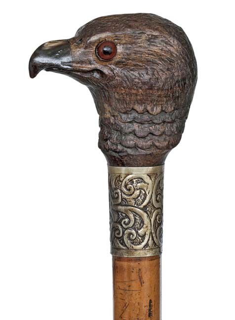 Carved Eagle Head Cane-19th Century-A naturalistica: Carved Eagle Head Cane-19th Century-A naturalistically carved hardwood eagle head with fine feather coat, curving horn beak and two red glass eyes. malacca shaft. chased metal collar and a long horn f