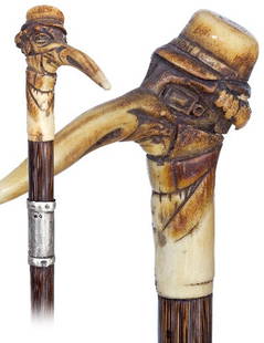 Staghorn Viennese Cane-19th Century-A carved portra: Staghorn Viennese Cane-19th Century-A carved portrait of a man with an exaggerated long nose wearing a square monocle and hat on a stepped partridge shaft with silver collar. -H. 3 ¾" x 3 ¼", O.L.