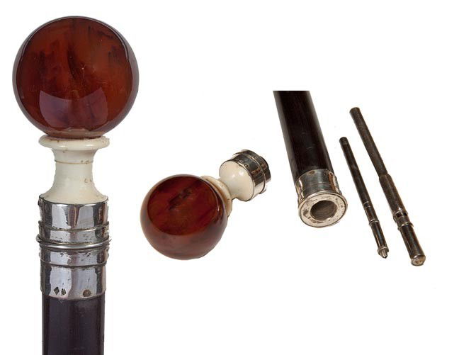 141. Amber/Ivory Snuff Cane-Circa 1880-An 1 ½" amb: 141. Amber/Ivory Snuff Cane-Circa 1880-An 1 ½" amber ball atop an ivory pedestal, .900 silver collars, handle unscrews to what appears to be a snuff spoon or other illegal substance, ebony shaft and