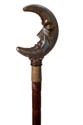 18. Horn "Man in the Moon Cane"-Early 20th Century-A ca: 18. Horn "Man in the Moon Cane"-Early 20th Century-A carved horn handle, ornate engraved brass collar, partrigewood shaft and a metal ferrule-H. 2 ½" x 3 ½", O.L. 37"