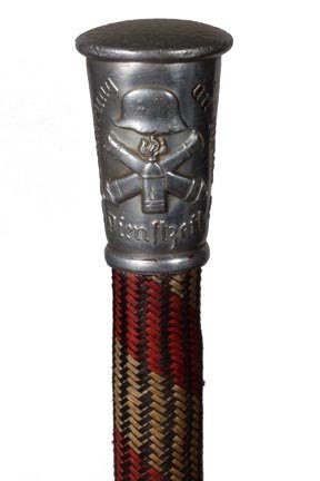 105. German Military Cane-Circa 1925-A cast metal top w: 105. German Military Cane-Circa 1925-A cast metal top with the words "Grinnerung Own Mpine Dienhzft" and a German helmet with cannons, woven shaft cover and a metal ferrule. H. 1 ¾" x 1", O.L. 36",