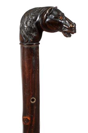103. Carved Horse Cane-Early 20th Century-A carved ebon: 103. Carved Horse Cane-Early 20th Century-A carved ebony horse with two color glass eyes, brass eyelets, twigspur shaft and a metal ferrule-H. 3” x 2”, O.L. 36”-