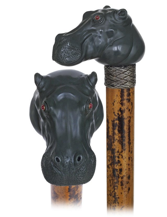 20. Figural Hard Stone Cane-Ca. 1890-Muddy green jasper: 20. Figural Hard Stone Cane-Ca. 1890-Muddy green jasper hippopotamus head on a malacca shaft with a braided silver wire collar and a metal ferrule. The joyous flair of the amphibious animal is accente