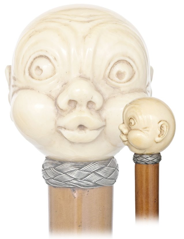 81. Figural Ivory Day Cane-19th Century-Ivory ball: 81. Figural Ivory Day Cane-19th Century-Ivory ball handle carved to depict a young boy’s head with a stunned expression on a snoopy face, malacca shaft with braided silver wire collar and an ivory f