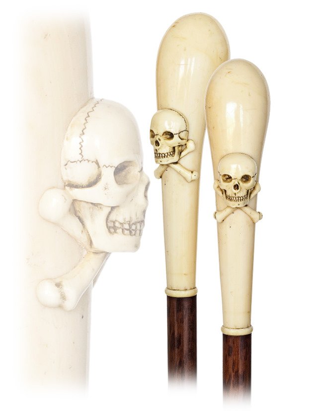 89. Memento Mori Ivory Cane-Ca. 1870-Substantial: 89. Memento Mori Ivory Cane-Ca. 1870-Substantial pistol-grip ivory handle carved with a human skull and bones on a snakewood shaft with an ivory collar and an ivory ferrule. This cane aged well and wi
