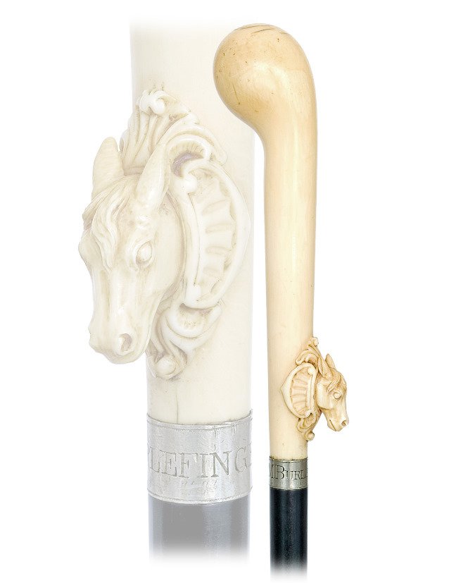 91. Ivory Turf Cane-Ca. 1880-Very large stretching: 91. Ivory Turf Cane-Ca. 1880-Very large stretching pistol shaped handle with a naturalistically carved horse head on a shield at the front. Ebony shaft with a plain silver collar engraved “M. BURLEF